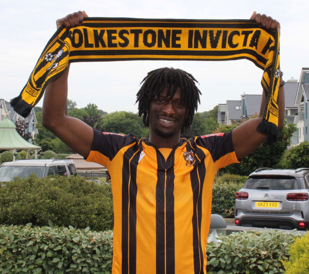 Andre Coker wearing a Folkestone Invicta shirt and holding a Folkestone Invicta scarf